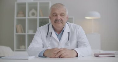 Doktorla online randevu, erkek doktor kameraya bakıyor ve başını sallıyor, aile terapistine video çağrısı yapıyor.