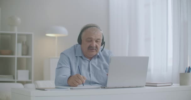 Boss komunikuje se zaměstnanci online chatem na notebooku, píše poznámky do sešitu, dává objednávky — Stock video