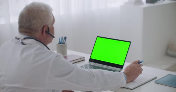 Online afspraak met therapeut, arts is met behulp van laptop met groene display voor chroma zeer belangrijke technologie, telegeneeskunde sessie — Stockvideo