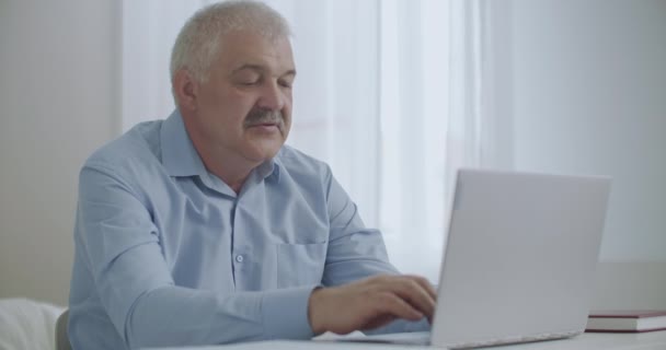 疲倦的男人在办公室里用笔记本电脑和伸出手来放松身体的腰带和脊椎，这都是工作时的健康问题 — 图库视频影像
