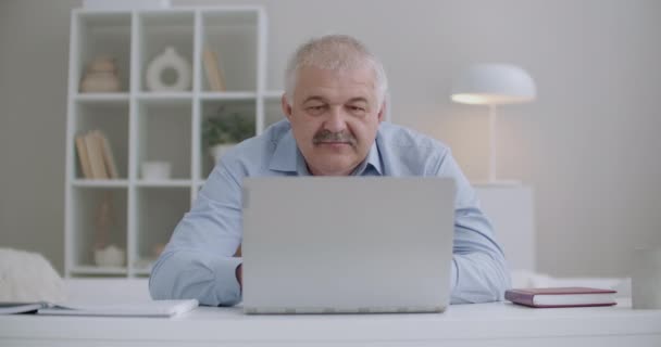 Idős férfi bajusszal dolgozik laptop, ül a szobában, válaszol az e-mail, gépelés szöveg üzenet, távolról munka otthonról — Stock videók