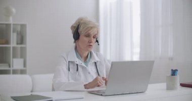 Terapistle online randevu, klinikte yaşlı bir kadın oturuyor ve internet üzerinden insanlara danışmanlık yapıyor.