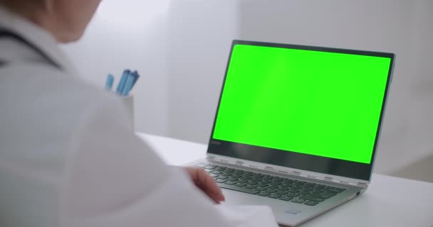 Ärztin berät sich online, schaut auf grünes Laptop-Display für Schlüsseltechnologie, hört zu und antwortet, gestikuliert mit den Händen — Stockvideo