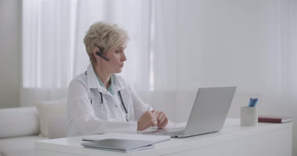 Kadın tıp profesörü internet bağlantısı olan bir dizüstü bilgisayar kullanarak ofisinden ders veriyor. — Stok video