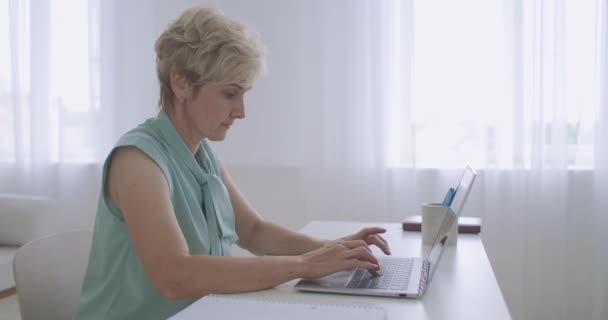 Oude secretaresse vrouw typt e-mail op het toetsenbord van laptop op kantoor, elektronische document workflow — Stockvideo