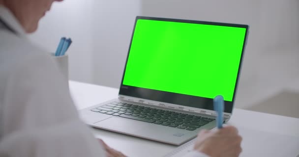 Ženský lékař poslouchá online přednášku ve videokonferenci na notebooku, zelenou obrazovku na notebooku pro technologii chromatografických klíčů, detailní pohled — Stock video