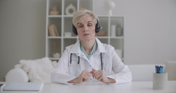 Μεσήλικη γυναίκα μιλάει διάλεξη από την ιατρική, γιατρός εξηγεί, κοιτάζοντας κάμερα, webinar ή σε απευθείας σύνδεση έννοια τηλεδιάσκεψης — Αρχείο Βίντεο