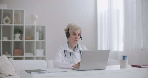 Orta yaşlı bir kadın, klinikteki ofisinden internetten insanlara danışmanlık yapıyor. — Stok video