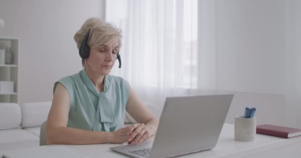Zkušená online konzultantka mluví online s klientem prostřednictvím video chatu na notebooku, pracuje vzdáleně z domova — Stock video