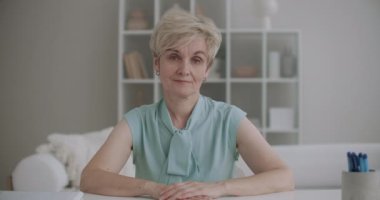 Çekici yaşlı kadının portresi kameraya bakıyor ve başını sallıyor, video çağrısı ve online sohbet konsepti.