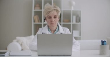 Kadın doktor, iş arkadaşları, hastalar veya stajyerler ile görüntülü konuşma teknolojisi ya da görüntülü konuşma teknolojisi kullanarak internet üzerinden iletişim kuruyor.