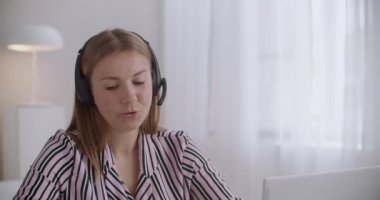 Kadın satış müdürü, IP telefonu, dizüstü bilgisayar ve kulaklık kullanarak müşteriyi arıyor.