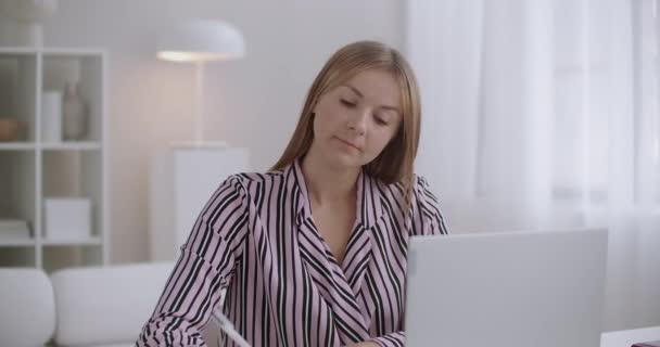Dor de dente de mulher jovem trabalhando com laptop e escrevendo notas em casa, sentindo dor aguda e tocar na bochecha — Vídeo de Stock