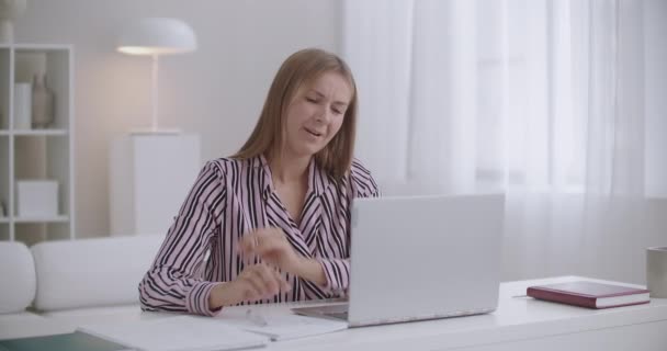 Mujer joven se siente dolor agudo en el cuello y el hombro durante el trabajo en la oficina en casa, charlando en línea y escribiendo en copybook — Vídeo de stock