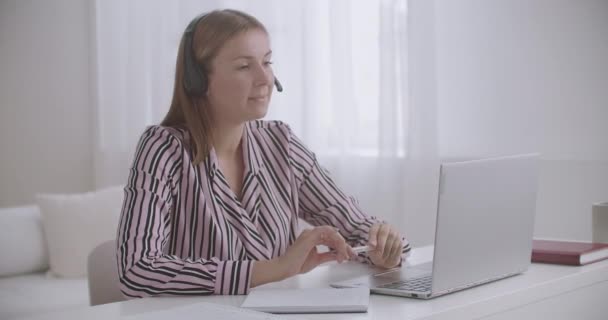 Jovem professora está conversando por videochat com alunos, ensinando online na pandemia de coronavírus — Vídeo de Stock