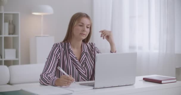 Mujer joven se está comunicando en línea por videollamada en el lugar de trabajo y sintiendo dolor de muelas agudo, mejilla conmovedora — Vídeo de stock