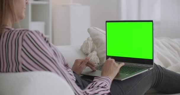 Estudante mulher está conversando on-line por laptop com tela verde para a tecnologia chave chroma, descansando em casa nos fins de semana — Vídeo de Stock