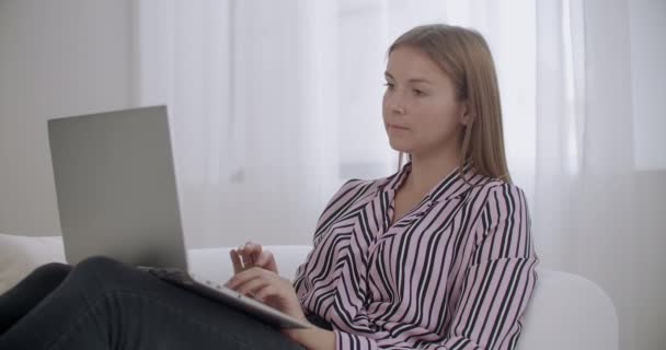 Mujer joven está navegando por Internet por ordenador portátil con wifi en casa, descansando y trabajando los fines de semana, en busca de información en Internet — Vídeos de Stock