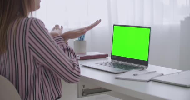Mladá žena si povídá videokalonem na notebooku, zelená obrazovka pro technologii chromatických klíčů, gestikuluje rukama — Stock video
