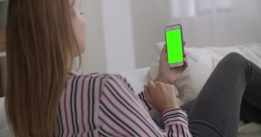 Genç bir kadın, internet üzerinden sohbet ederek krom anahtar teknolojisi için yeşil ekranlı modern akıllı telefonlarda video çağrısı yapmak için uygulama kullanıyor.