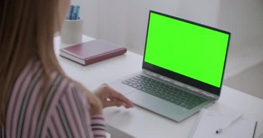 Krom anahtar teknolojisi için yeşil ekran, not defterindeki video aracılığıyla çalışan ve iletişim kuran kadın konuşuyor