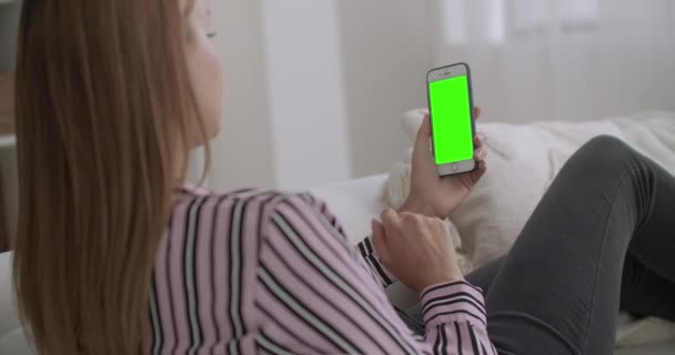 Young woman is using app for video calling in modern smartphone with green screen for chroma key technology, chatting by internet — Stock Video