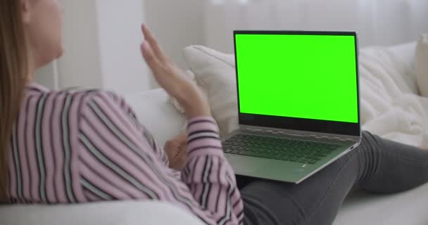 Ung avslappnad kvinna använder bärbar dator med grön skärm för chroma nyckel teknik för att chatta på internet, ringer via videochatt — Stockvideo