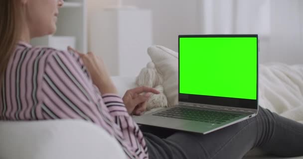 Mulher alegre está usando chamada de vídeo no laptop para se comunicar com o amigo, tela verde no notebook para a tecnologia chave chroma — Vídeo de Stock