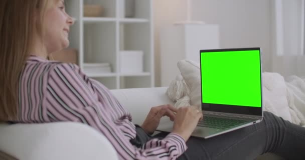 Жінка розмовляє онлайн, використовуючи відео чат на ноутбуці, зелений екран на ноутбуці для технології ключа хроми — стокове відео
