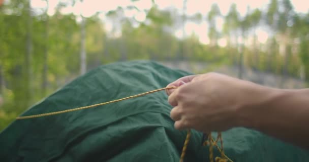 Porträtt av en man som sätter upp ett tält i skogen i slow motion — Stockvideo
