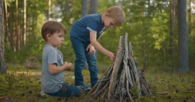 Yürüyüş sırasında iki çocuk ormanda bir ateşe çubuk koydu. Ormandaki çocuklar ateş yakıp çubukları birleştirmeye hazır olun. 