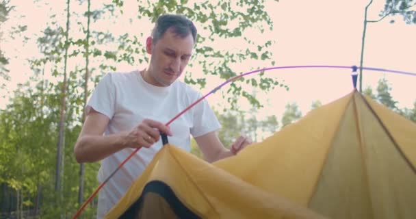 Retrato de um homem montando uma tenda na floresta em câmera lenta — Vídeo de Stock