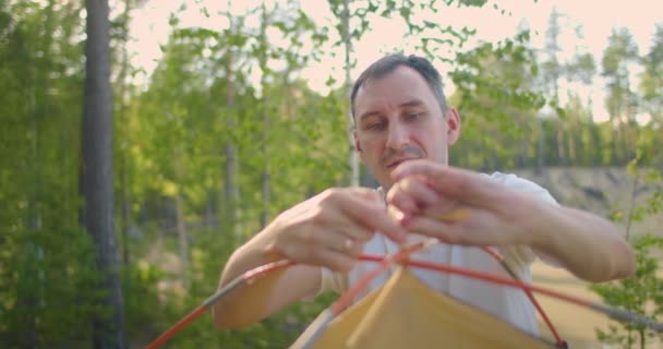 Retrato de un hombre instalando una tienda en el bosque en cámara lenta — Vídeo de stock