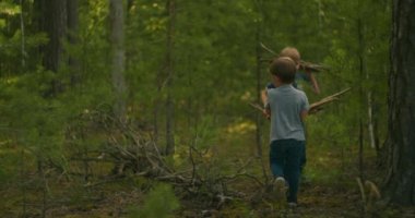 Ormanda iki çocuk ateş için odun topluyor. 3-6 yıllık adam ormanda yangın için odun topluyor.