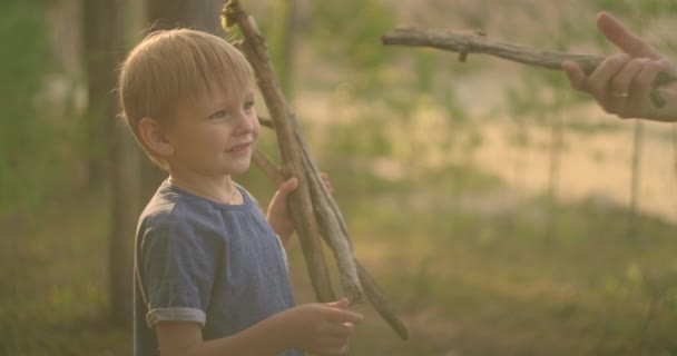 Anak itu mengumpulkan tongkat di hutan dan memberi ayahnya pistol tongkat dari pohon. Tampilkan temuan — Stok Video