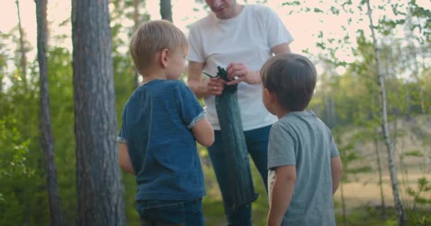 Отец и двое сыновей 3-5 лет вместе в походе установили палатку — стоковое видео