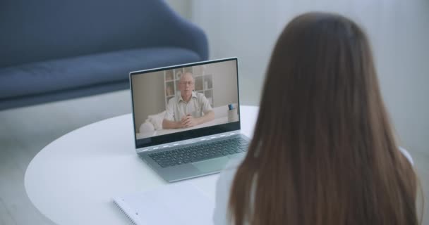 自宅でラップトップ上の教師とのビデオ会議の高角度ビュー。ビデオ通話の女の子は、コンピュータの音声コース、距離とeラーニング教育の概念を聞く上で個人的な家庭教師と. — ストック動画