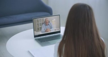 Evde dizüstü bilgisayarlı öğretmenle yüksek açılı video konferansı. Videodaki kız, kişisel öğretmeniyle birlikte bilgisayar dinleme kursunda, uzaktan ve e-öğrenim konseptinde..