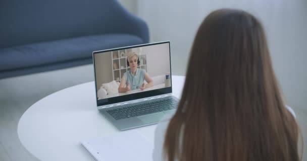 Educación a distancia en línea. Una mujer estudia en casa y Elearning zoom videollamada. Un hogar de aprendizaje a distancia. Vista por encima del hombro. — Vídeos de Stock