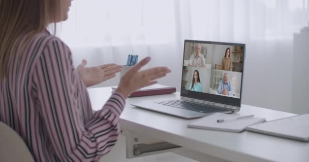 Vista posterior de la mujer empleada hablan de hablar en videollamada con diversos colegas multirraciales en la sesión informativa en línea, mujer trabajadora tiene Webcam conferencia de grupo con compañeros de trabajo en la computadora portátil moderna en casa — Vídeos de Stock