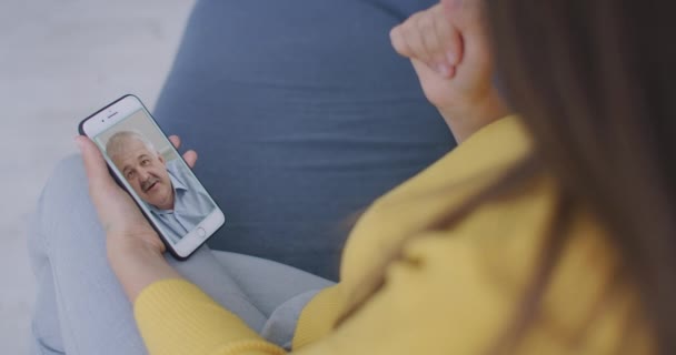 Sopra la spalla vista di giovane donna figlia video chiamare vecchio padre genitore o amico maturo utilizzando conferenza chat applicazione online sullo schermo del telefono cellulare a casa ufficio. Concetto di videocall familiare — Video Stock