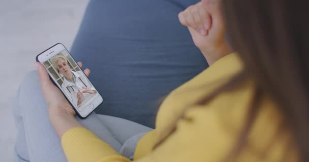 Arzt oder Therapeut helfen, Stress durch Coronavirus-Krise zu überwinden Videokonferenzschaltung online Live-Talk mit Frau sitzen auf Sofa Couch zu Hause mit Smartphone Arztkonsultation. — Stockvideo