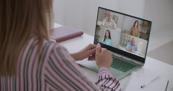 Vista posterior de la mujer de negocios hablando con sus colegas sobre el plan en la videoconferencia. Equipo de negocios multiétnicos que utiliza el portátil para una reunión en línea en videollamada. Grupo de personas inteligentes que trabajan desde casa — Vídeo de stock