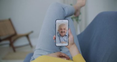 Genç bir kızın, yaşlı bir ebeveyni ya da olgun bir arkadaşını cep telefonu ekranında konferans chat uygulamasını kullanırken görüntülediği görüntüler. Aile video çağrısı kavramı