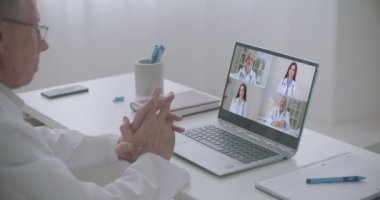 Erkek doktor, iş arkadaşlarıyla laptopta video konferansı yapıyor. Corona virüsünün ihtiyati önlemleri hakkında doktorları dinleyin, video konferans laptop webcam görüntüsü