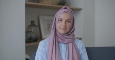 Kameraya bakıp başını sallayan tesettürlü Müslüman bir kadın video bağlantısıyla konuşuyor ve konferans dinliyor. Uzak video sohbeti