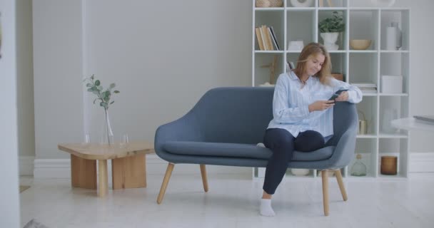 Retrato de mujer de negocios feliz disfrutar del éxito en el teléfono móvil en la oficina en casa. Primer plano alegre chica leyendo buenas noticias en el teléfono en cámara lenta. Señora sorprendida celebrando la victoria por teléfono en el apartamento. — Vídeos de Stock