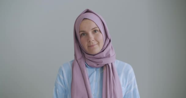 Mirando a la cámara y asintiendo con la cabeza, una mujer musulmana en un hiyab está hablando en un enlace de video y escuchando una conferencia. Conversación remota de vídeo — Vídeos de Stock