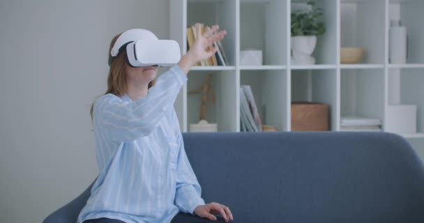 Jong meisje in virtual reality headset scrollen in de lucht thuis Technologie concept. jonge vrolijke vrouw dragen virtual reality headset kijken 360 VR video film zitten in het bed thuis. — Stockvideo