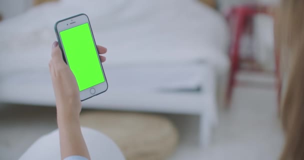 Vrouw die Smart phone gebruikt en zoekt Groen scherm thuis. jong meisje houdt Smartphone met groene scherm op avond tijd. — Stockvideo